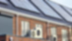 New red brick build development with solar panels on the roof and modern air source heat pump installed for sustainable energy efficiency.