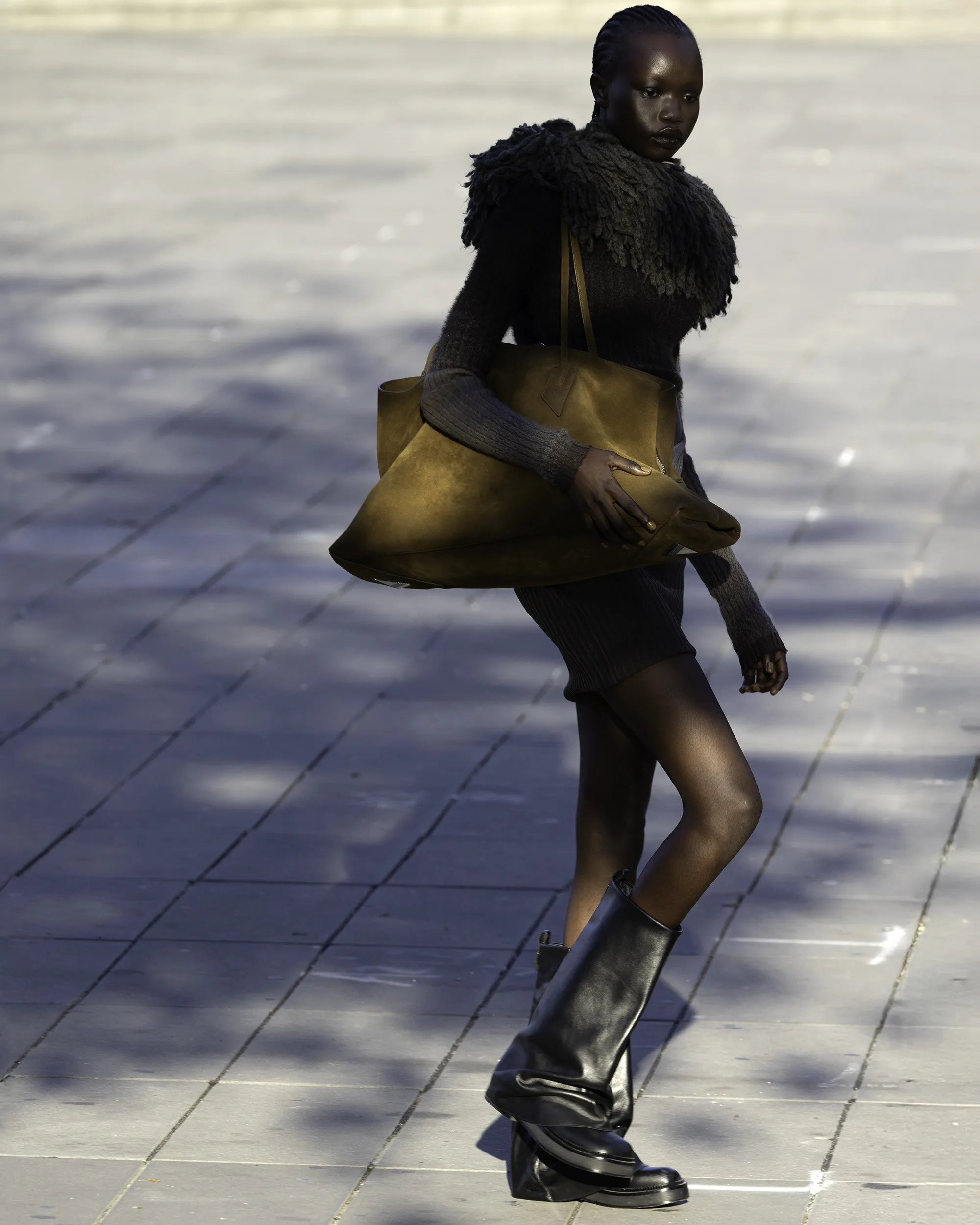 Bronze statue of a woman in fashionable clothing on a sunny day.