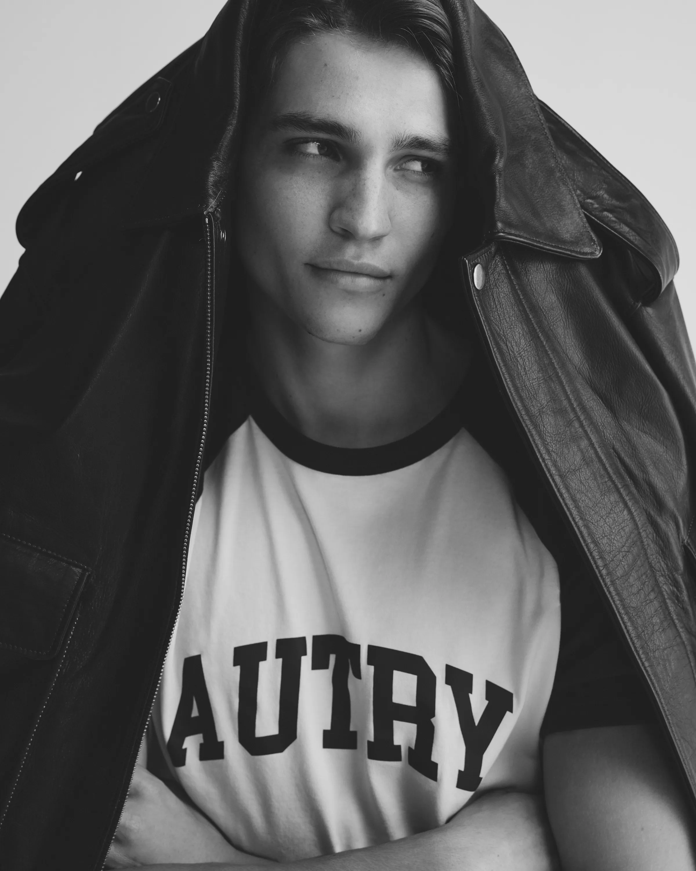 Young man with leather jacket and AUTRY shirt posing in studio setting