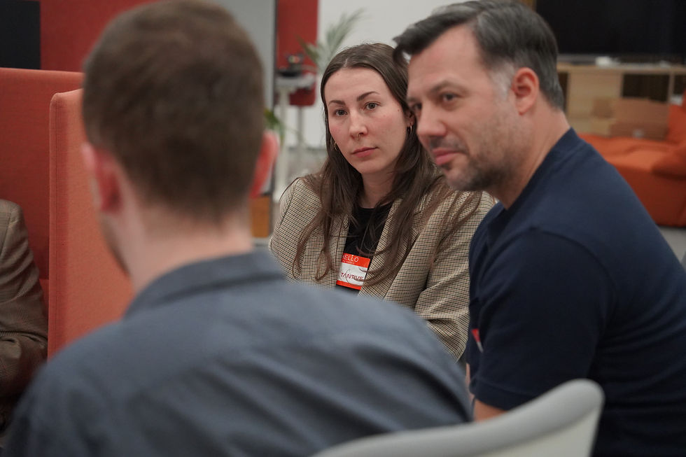 Drei Personen diskutieren in einem modernen Raum mit orangefarbenen Sesseln.