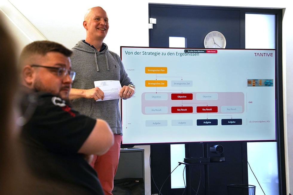 Objectives & Key Results? Agile Coach Sebastian Kraus stellt im Quartalsmeeting auf einem Bildschirm die OKR-Methode vor. 