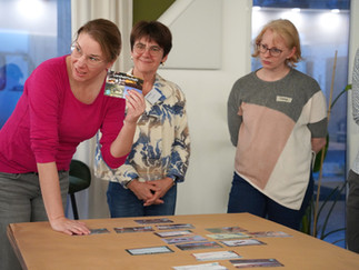 Galerie, die verschiedene Gruppen beim Spielen des Klimapuzzles an Tischen zeigt.