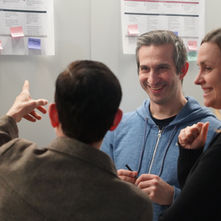 Drei Crew Member diskutieren vor einem Whiteboard.