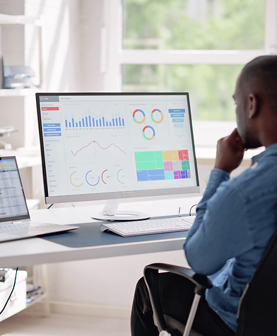 A professional analyzing data on a large computer screen displaying charts, graphs, and performance metrics, representing business intelligence and strategic decision-making.