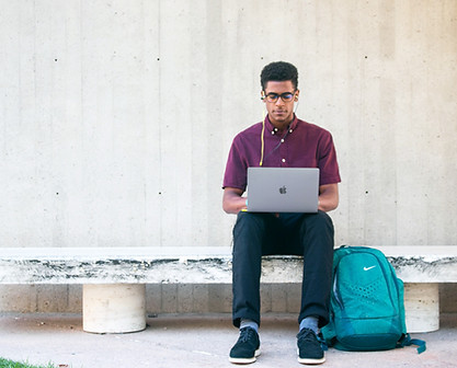 Jovem negro estudando ao ar livre com seu computador