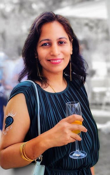 Portrait of Ranjana Joshi smiling, holding a glass at an outdoor event (author photo)