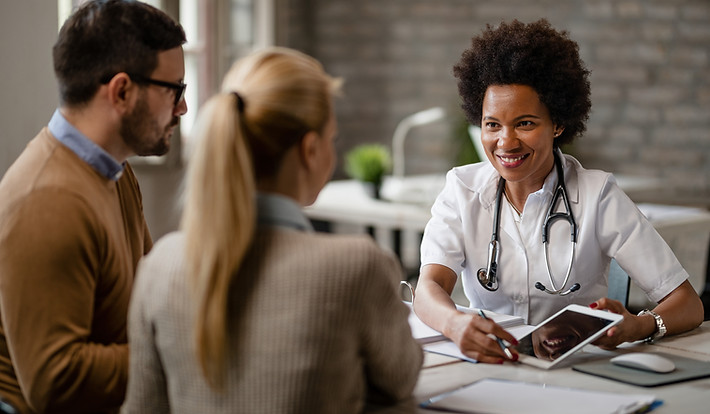 happy-black-female-doctor-talking-couple-showing-them-medical-test-results-touchpad-consul