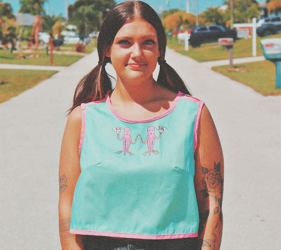 A stylish young lady in a green crop top with pink piping featuring a vintage japaneese matchbook cover on the front as a statement