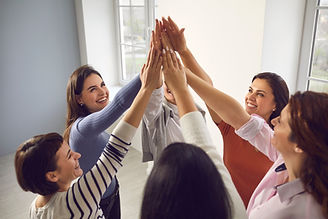 Team of happy confident smiling young women standing in circle and putting hands together,