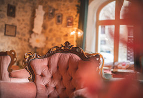 Un fauteuil rose orné dans un salon avec une fenêtre et des décorations.