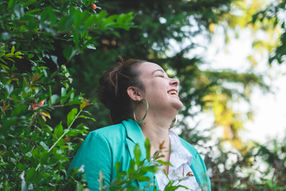 Une femme joyeuse porte une veste verte et sourit, portrait extérieur.