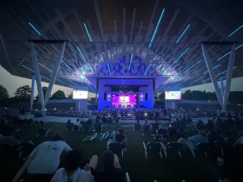 Outdoor VeeCon festival stage with large LED displays and audience during evening programming