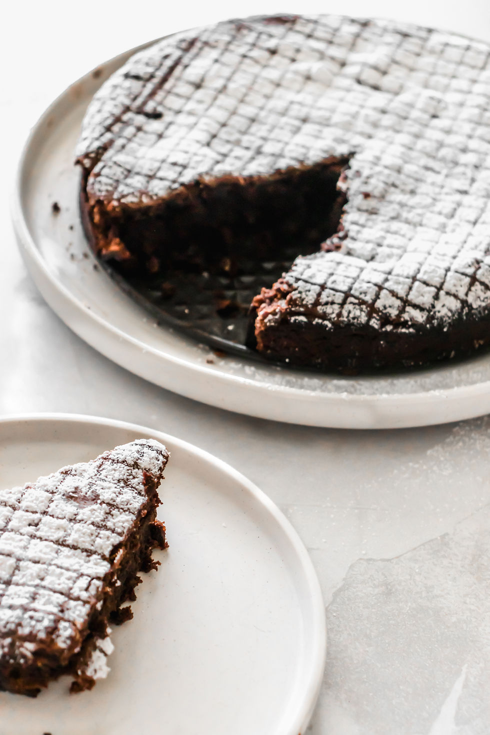 Vertical shot of caprese cake and a slice on a plate