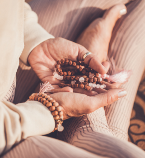 Lady sitting cross-legged cupping a mala in her hands