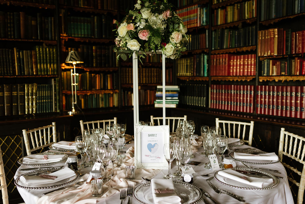 tall flower arrangements on white stands in library 