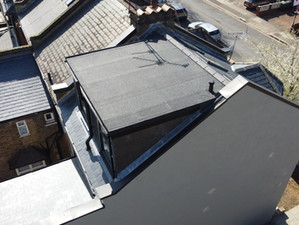 An aerial shot of a loft extension with a flat roof, black cladding, and large windows.