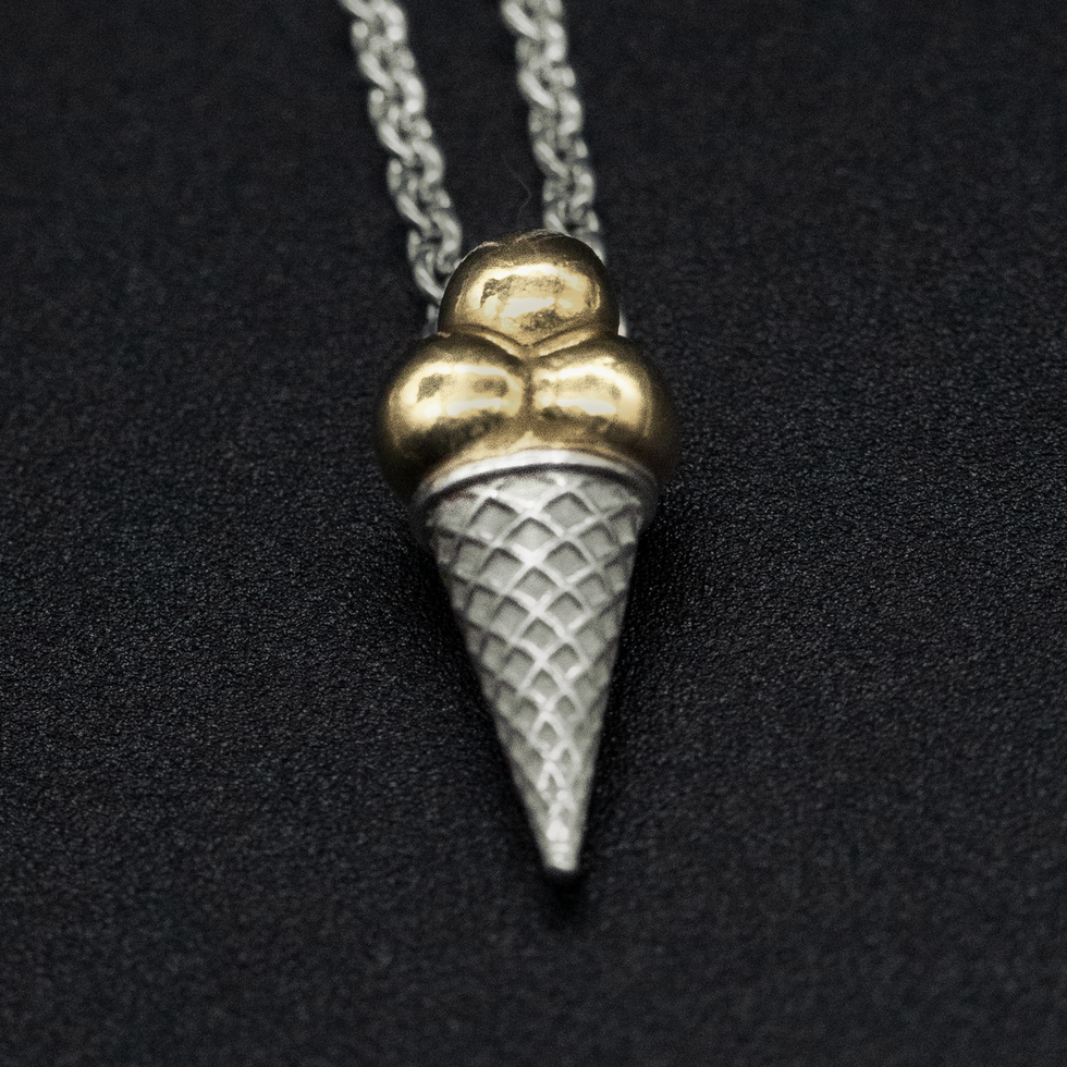 Handcrafted sterling silver pendant shaped as an ice cream cone with gold plated scoops and textured cone pattern, shown on s