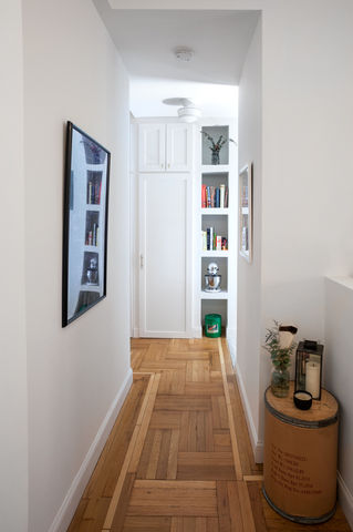 Hallway with wood parquet, framed art, and built-in shelves