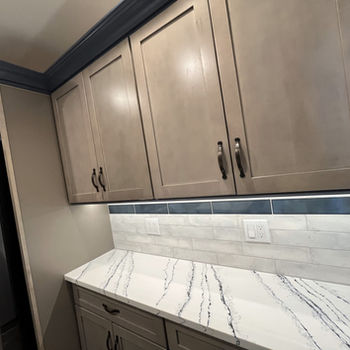 Gray kitchen cabinets, veined counter, white subway tile