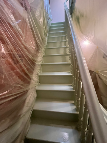 Freshly painted basement stairs with plastic covered walls
