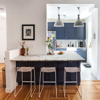 Modern kitchen with navy cabinets, marble island, and stools