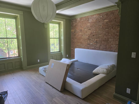 Unfurnished bedroom with green walls, brick, and bed frame