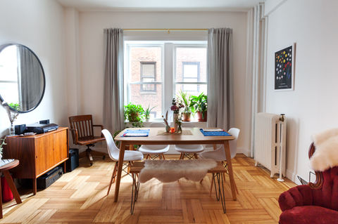 Modern dining area with wood table, white chairs, and window plants