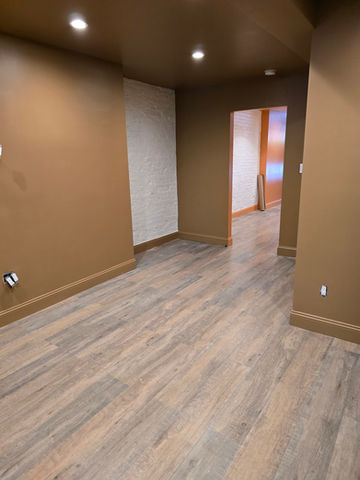 Finished basement room with brown walls and wood-patterned floor