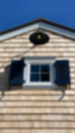Gambrel carriage house window with classic shutters and hold backs