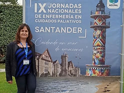 Patricia, vicepresidenta de ASAG, posa junto al cartel sobre las jornadas nacionales de enfermería en cuidados paliativos.