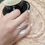 Thumbnail: El anillo luce las siluetas de la rama y la hoja entre los dedos de la mano de la modelo que sujeta su tasa de café,