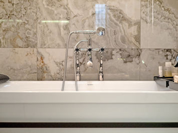 Luxury bathroom in Edgbaston with marble-effect tiles, freestanding bath, walk-in shower, double vanity, and black and chrome fixtures.