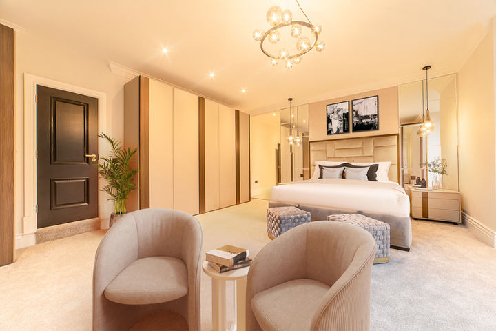 Luxurious bedroom renovation in Birmingham with bespoke wardrobes, upholstered bed, pendant lighting, and soft neutral tones throughout the space.