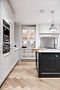 Modern kitchen with white cabinets, dark island, and herringbone floor