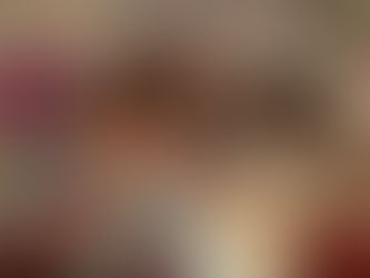 Three young adults sit closely together on a bed, smiling at the camera with their arms around each other. The room is warmly lit with floral wall art, soft curtains, and a cozy bedroom setting, creating an intimate, joyful atmosphere that suggests friendship, closeness, and shared memories.