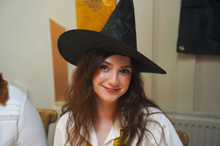Woman smiling in a witches hat & school uniform.