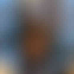 Woman smiling while playing the guitar in front of a microphone stand.