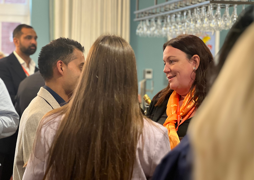 Woman wearing an orange scarf engaged in conversation with two other people.