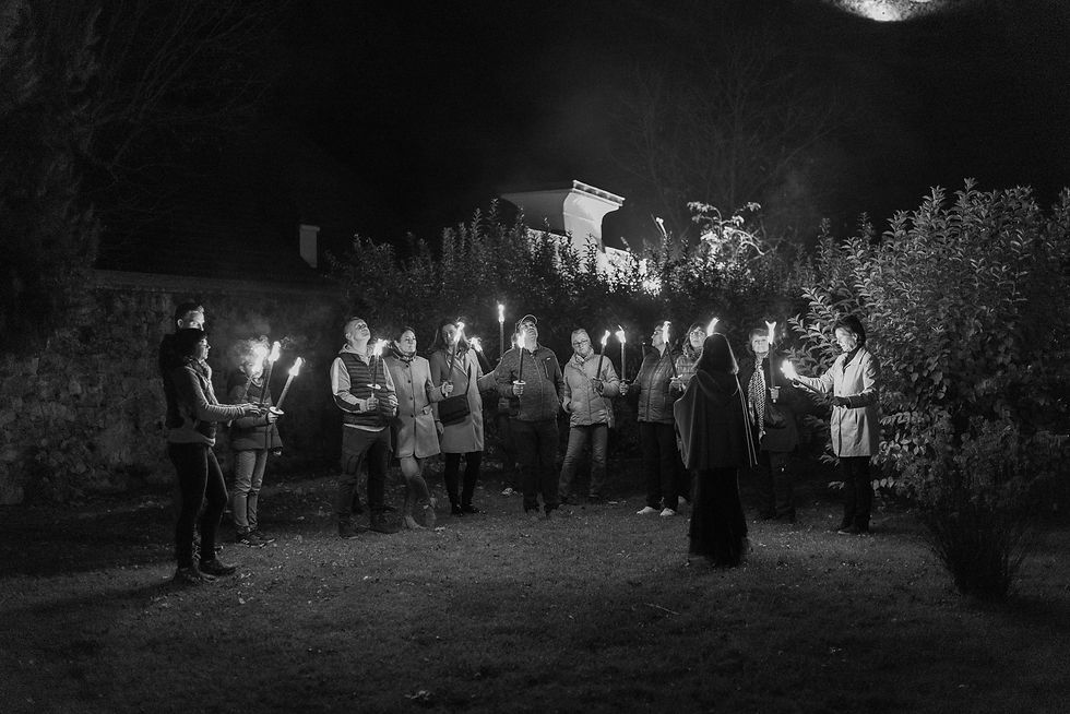 Eine Gruppe von Menschen steht bei Nacht im Freien und hält brennende Fackeln. In der Mitte steht eine Fremdenführerin und spricht zur Gruppe. Die Szene zeigt eine nächtliche Stadtführung in Friesach in ruhiger, stimmungsvoller Atmosphäre.