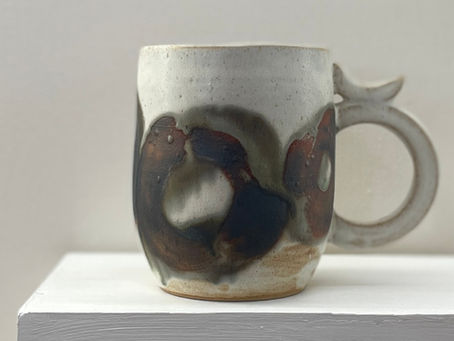 A handmade white ceramic mug with dark Enso brushmark