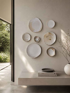 A wall art composition made out of handmade plates in a palette of white
