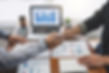 Two business people shaking hands in front of computer
