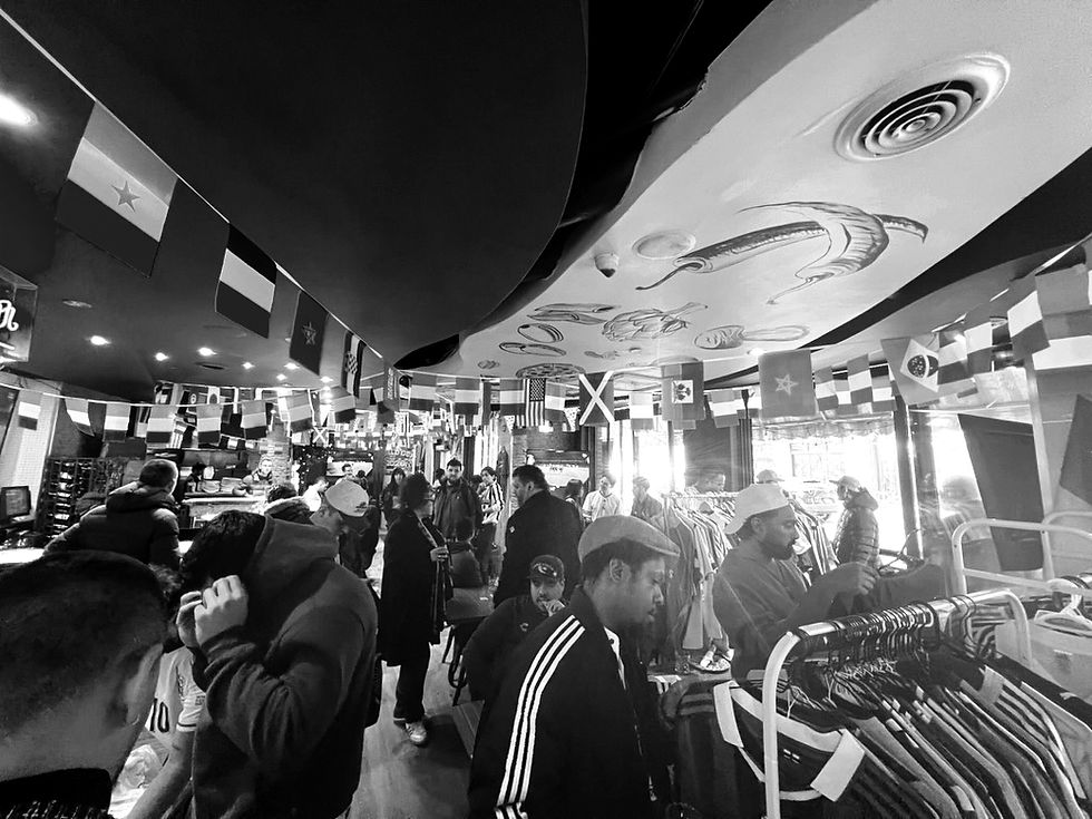 Packed Toronto restaurant hosting a T26 by Matchday Social soccer kit market event, with racks of football jerseys from clubs around the world, international flags, and a live match on screen — list your venue and get discovered by football supporters across North America
