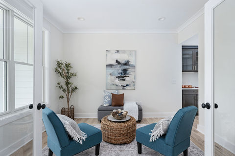 Bright sitting room with two blue armchairs and abstract art