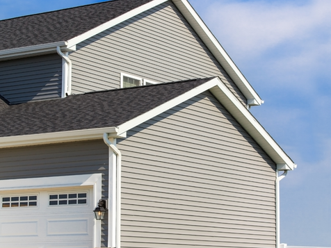 Professional siding installation featuring horizontal grey vinyl siding and white rain gutters.