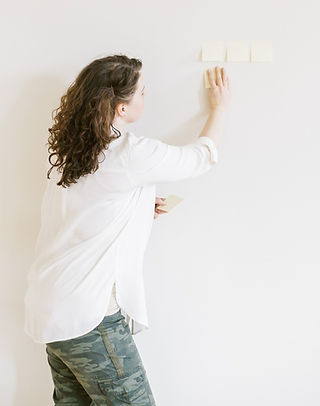 Sarah Panus facing a wall arranges post it notes while she thinks through a content plan