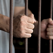 The hands gripping the prison bars symbolize helplessness and imprisonment.