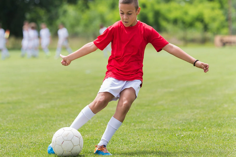 A kid soccer player kicking the ball