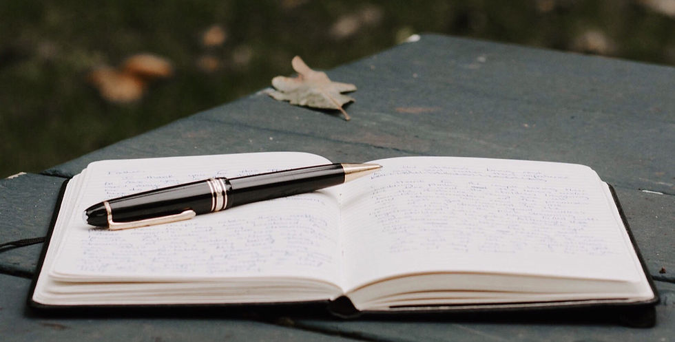 pen on open journal on a picnic bench in fall