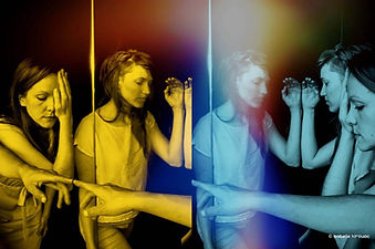 Two dancers perform with mirrored reflections and vivid yellow-to-blue colour overlays in an immersive installation.